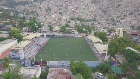 Antena-Sobre-Los-Barrios-De-Tugurios-Favela-Y-Barrios-De-Chabolas-En-El-Distrito-De-Cite-Soleil-De-Port-Au-Prince,-Haití-Con-Estadio-De-Fútbol-En-Primer-Plano-1