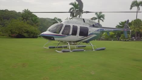 Bewegen-Sie-Sich-In-Der-Luft-Eines-Sandalen-Resort-Hubschraubers,-Der-Auf-Einer-Grasbewachsenen-Offenen-Fläche-Auf-Einer-Luxuriösen-Tropischen-Insel-In-Jamaika-Sitzt