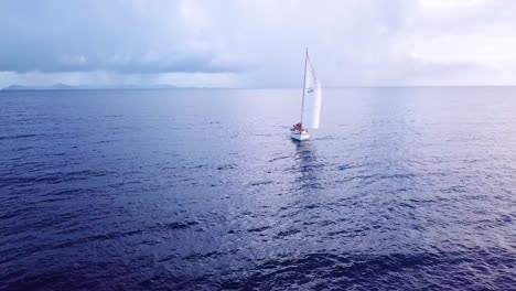 Beautiful-aerial-of-young-people-on-a-sailboat-sailing-across-the-Caribbean-ocean-sea-near-the-island-of-St-Vincent-1