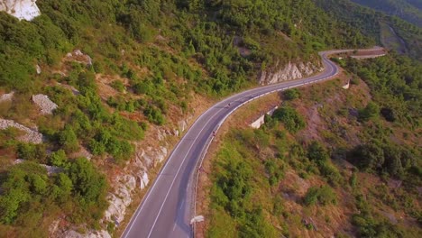 Aerial-over-three-people-riding-mopeds-or-Vespa-scooters-along-a-two-land-mountain-road-in-Croatia