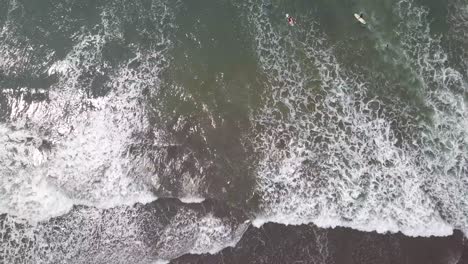 Aerial-shot-looking-straight-down-at-surfers-in-waves-