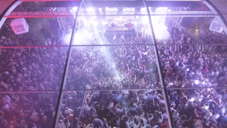 Aerial-over-a-massive-indoor-outdoor-rock-concert-or-dance-club-at-night-with-huge-crowds-partying-and-dancing
