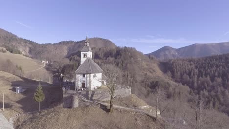 Nice-vista-aérea-of-a-small-white-church-in-the-mountains-of-Slovenia