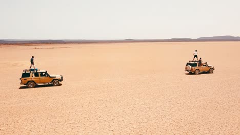 Good-aerial-of-jeeps-in-road-rally-driving-across-Somalia-with-tourists-leaning-out-and-riding-on-roof-celebrating-1