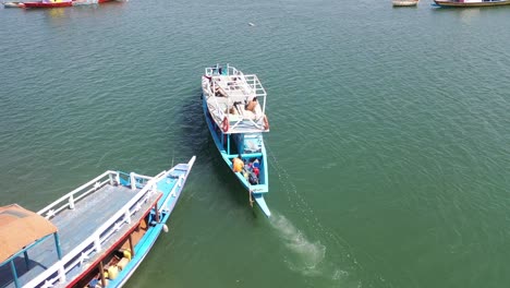 Antena-Sobre-Un-Barco-Turístico-De-Madera-Que-Sale-De-Un-Pequeño-Puerto-Y-Se-Dirige-Hacia-El-Río-Gambie-Cerca-De-Banjul,-Gambia