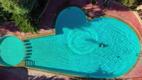 Antena-De-Drone-Ascendente-De-Un-Hombre-De-Zambullirse-En-Una-Piscina-De-Hotel-Resort-Verde-Con-Forma-De-Submarino