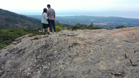 Aerial-Man-And-Woman-Climb-A-Rock-And-Take-Selfie-Photos-Overlooking-Santa-Barbara-California