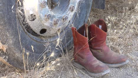 Cowboy-Boots-Sit-At-The-Base-Of-A-Rusted-Vehicle-Tire-As-A-Memorial-To-A-Retired-Cowboy