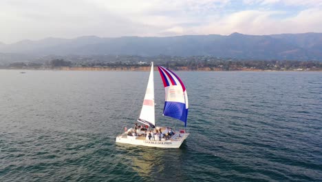 Antena-Sobre-Un-Catamarán-De-Vela-Navegando-Frente-A-La-Costa-De-Santa-Bárbara,-California-1