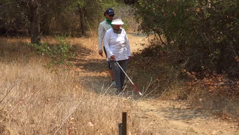 A-Blind-Woman-Walks-With-A-Cane-Through-A-Natural-Area-With-A-Guide-Helping-Her-Explore-The-Wilderness-4