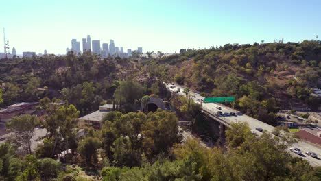 Aerial-Freeway-Cars-Travel-Along-The-110-Freeway-In-Los-Angeles-Through-Tunnels-And-Towards-Downtown-Skyline