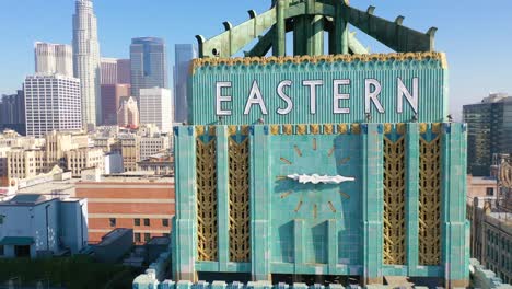 Aerial-Of-The-Historic-Eastern-Building-In-Downtown-Los-Angeles-With-Clock-And-Downtown-City-Skyline-Behind-2