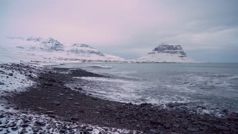 A-rock-harbor-is-seen-with-snowy-town-of-Grundarfjordur-Iceland-in-the-background