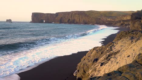 Waves-lap-at-the-black-sand-beach-near-the-rock-arch-of-Dyrholaey-Iceland