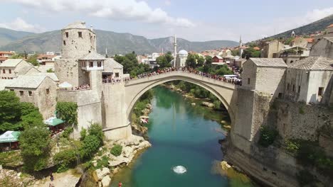 Un-Hombre-Se-Zambulle-Desde-El-Abarrotado-Puente-Mostar-Hacia-El-Río-Neretva-Abajo-En-Mostar-Bosnia