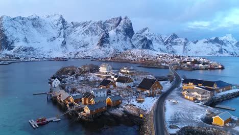Una-Ciudad-En-Las-Islas-Lofoten-Noruega-Se-Ve-Con-Montañas-Cubiertas-De-Nieve-En-La-Distancia