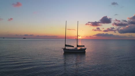 Ein-Mann-Wird-Bei-Sonnenuntergang-In-Einem-Kanu-In-Der-Nähe-Eines-Segelbootes-In-Thailand-Gesehen
