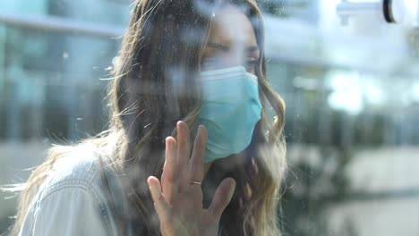 A-cleared-woman-with-mask-is-separated-or-isolated-from-a-loved-one-by-a-glass-window-during-coronavirus-pandemic-1
