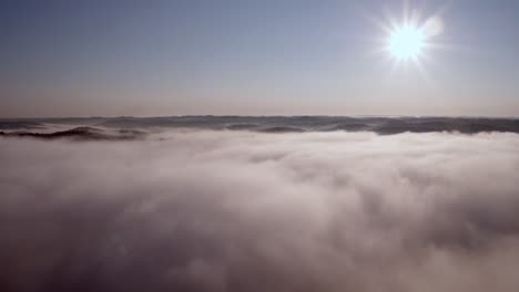 Aerial-Over-Clouds-And-Mountains-With-the-Sun-In-the-Right-Corner