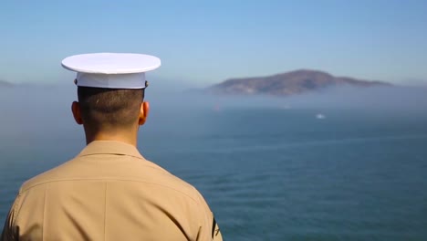 A-Navy-Ship-Passes-By-San-Francisco-Landmarks-Including-Alcatraz-And-The-Bay-Bridge