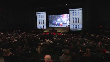 John-Glenn-Funeral-Motorcade-Moves-Down-A-City-Street-And-Is-Projected-Before-A-Large-Audience