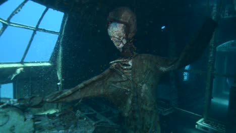Underwater-footage-of-scuba-divers-exploring-a-sunken-plane-in-the-Red-Sea-with-skeleton-pilot