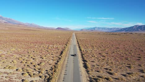 Aerial-of-a-4WD-wheel-drive-vehicle-on-a-paved-road-across-the-Owens-Valley-desert-region-suggests-remote-Eastern-Sierra-adventure