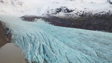 Antenne-Eines-Gletschers,-Der-Von-Einer-Schneebedeckten-Bergkette-In-Island-Gefroren-Ist-1