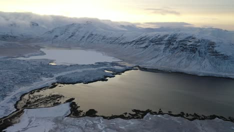 Eine-Luftaufnahme-Zeigt-Schneebedeckte-Berge,-Die-Einen-See-In-Island-Umkreisen