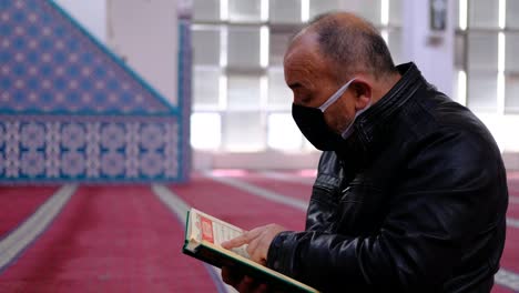 älterer-Mann-Trägt-Maske-Und-Liest-Den-Koran-In-Der-Moschee