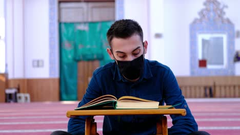 Junger-Mann-Trägt-Eine-Maske-Und-Liest-Den-Koran-In-Der-Moschee