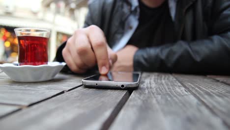 Young-Man-Using-His-Smartphone-In-A-Cafe-Close-Up-Hands-1