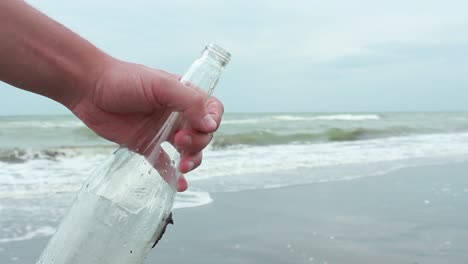 Young-Man-Closing-Message-In-A-Bottle-On-Sand-Beach