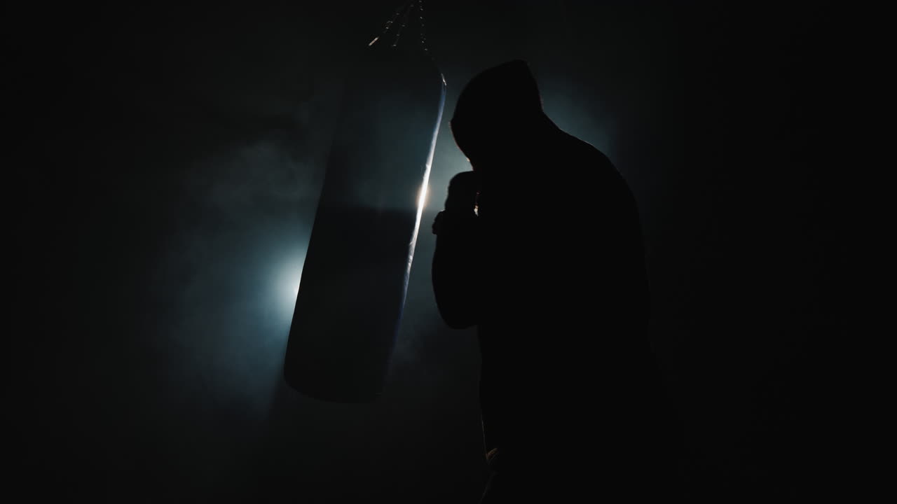 Premium stock video - Side view of boxer training in a spotlight