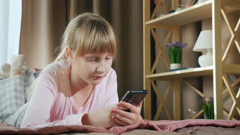 Blonde-girl-uses-a-smartphone-in-her-bedroom