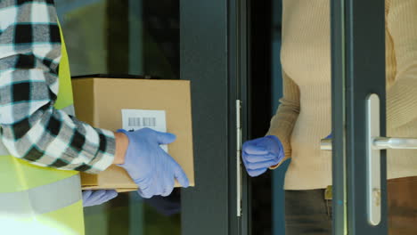 A-courier-wearing-a-protective-gloves-delivers-a-parcel