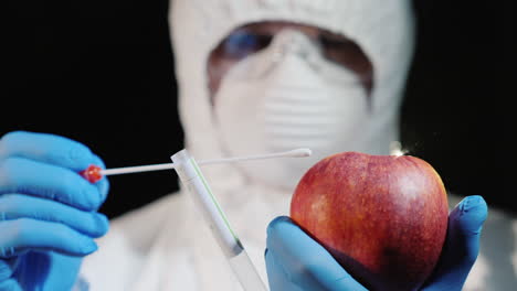 A-man-in-protective-clothing-and-gloves-takes-a-smear-from-a-large-apple