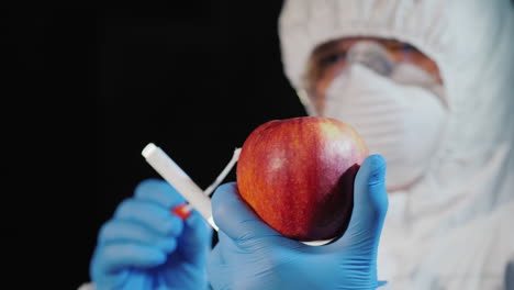 A-man-in-protective-clothing-and-gloves-takes-a-smear-from-a-large-apple-1