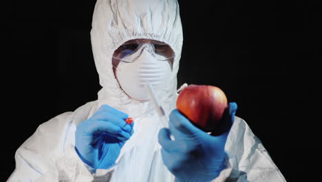 A-man-in-protective-clothing-and-gloves-takes-a-smear-from-a-large-apple-4