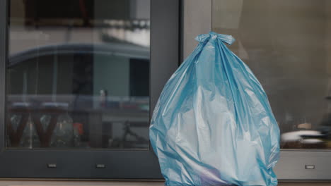Man-Puts-A-Bag-Of-Household-Rubbish-On-The-Doorstep-Of-The-House