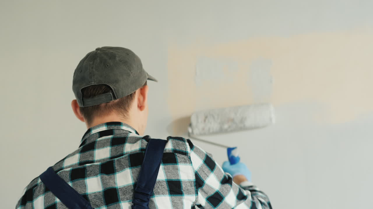 Premium stock video - Male builder paints wall with roller