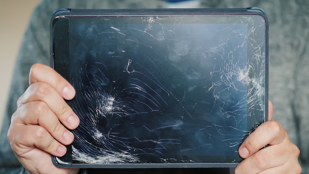 Premium stock video - A man holds a tablet with a broken screen