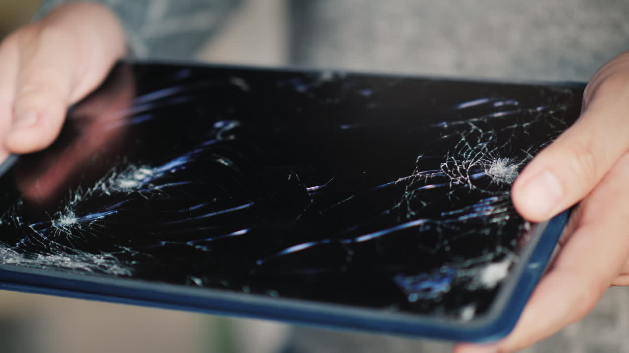 Premium stock video - A man holds a tablet with a broken screen 2