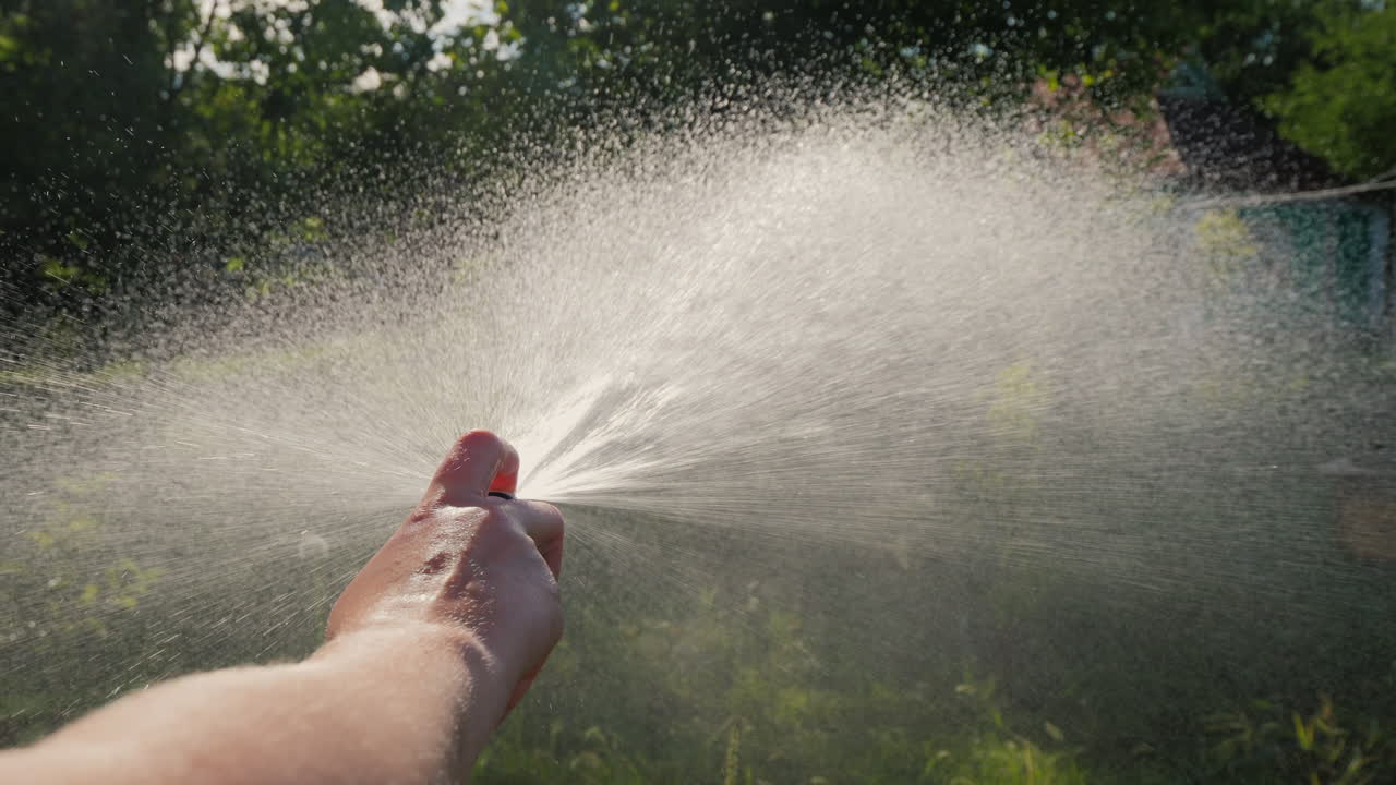 Premium stock video - Gardener's hand pours a garden hose with a diffuser