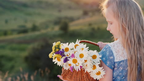 A-child-holds-a-basket-of-flowers-stands-in-a-meadows-and-green-hills-1