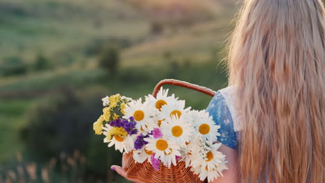 A-child-holds-a-basket-of-flowers-stands-in-the-green-hills