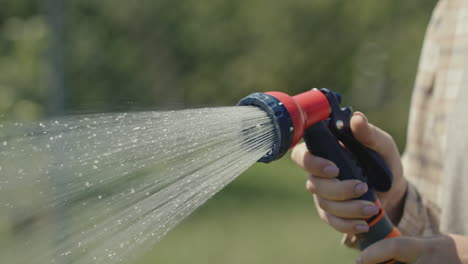 Gardener's-hand-sprays-a-garden-hose-with-a-diffuser