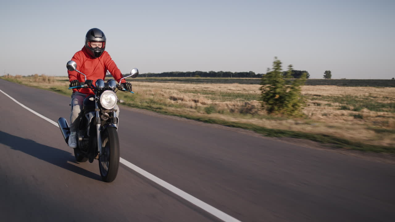Vídeo Premium Un joven monta una moto a lo largo de los campos de maíz