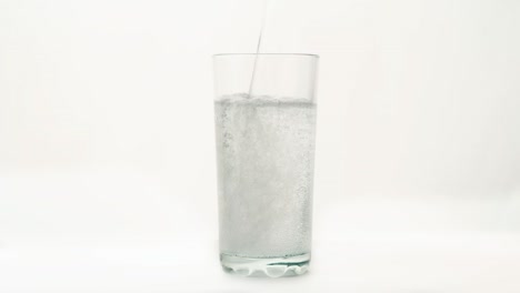Water-is-poured-into-a-glass-on-a-white-background