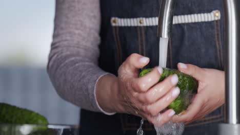 A-woman-washes-cucumbers-under-a-stream-of-water-from-a-tap